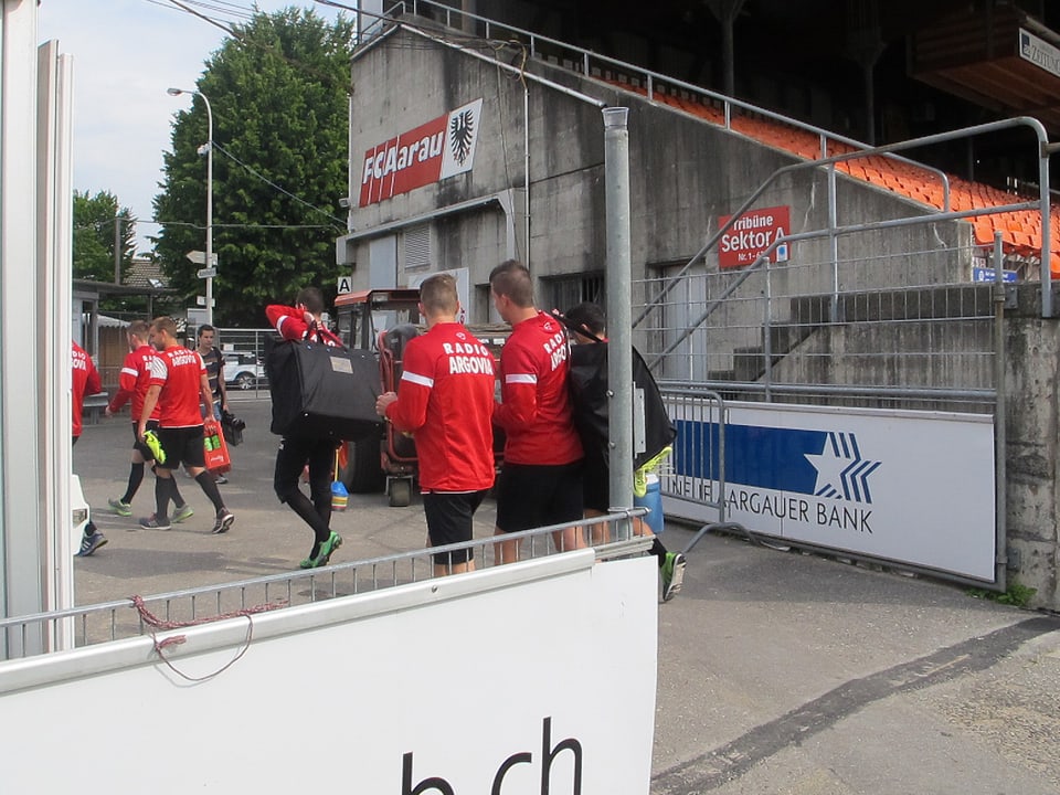 Spieler neben der Stadiontribüne mit Gepäck.