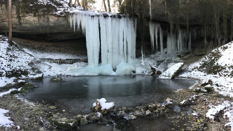 Eiszapfen hängen in Hombrechtikon über einen kleinen Wasserfall.