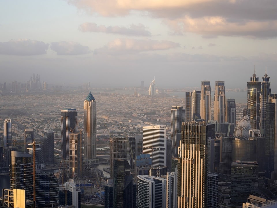 Aerial view of modern city with tall buildings under cloudy sky.