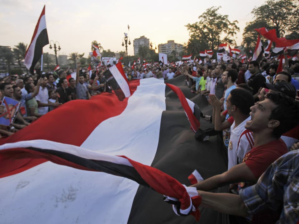 Mursi-Gegner singen mit einer meterlangen Ägypten-Flagge in den Händen vor Präsidenten-Palast «Qasr Al Quba» in Kairo. (reuters)