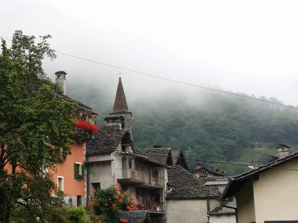 Ein typisches Tessiner Dorf mit einem Kirchturm und den farbigen Hauswänden.