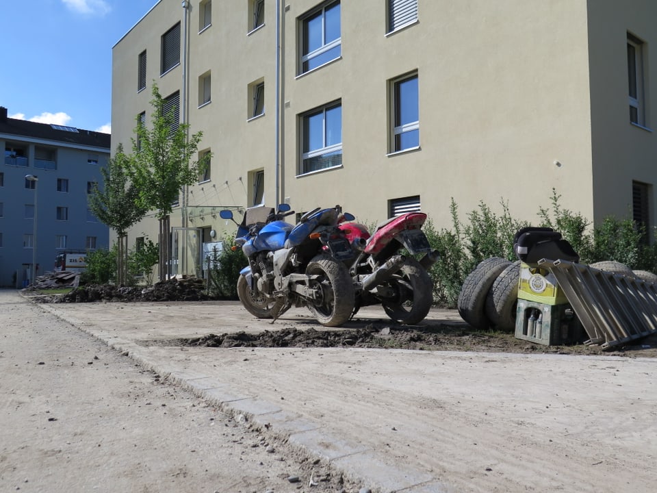 Zwei beschädigte Motorräder vor einem Mehrfamilienhaus.