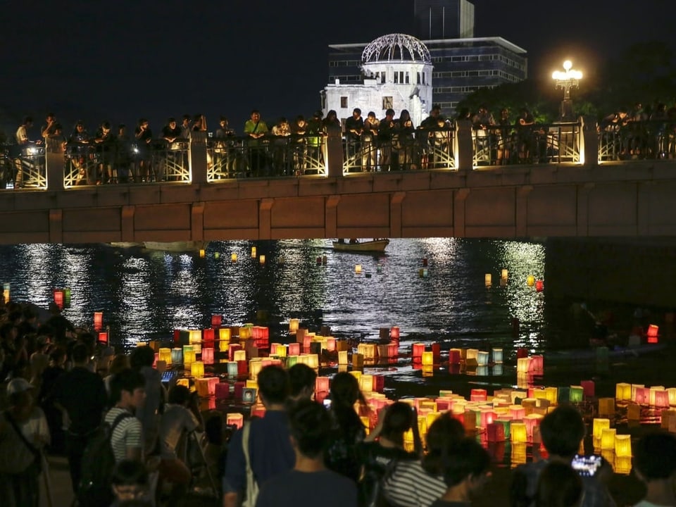 Viele Menschen begehen den Hiroshima-Jahrestag und legen bunte Laternen aufs Wasser.