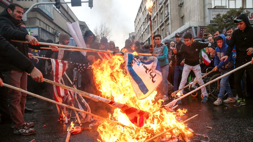 Menschen verbrennen Flaggen der USA und Israel.