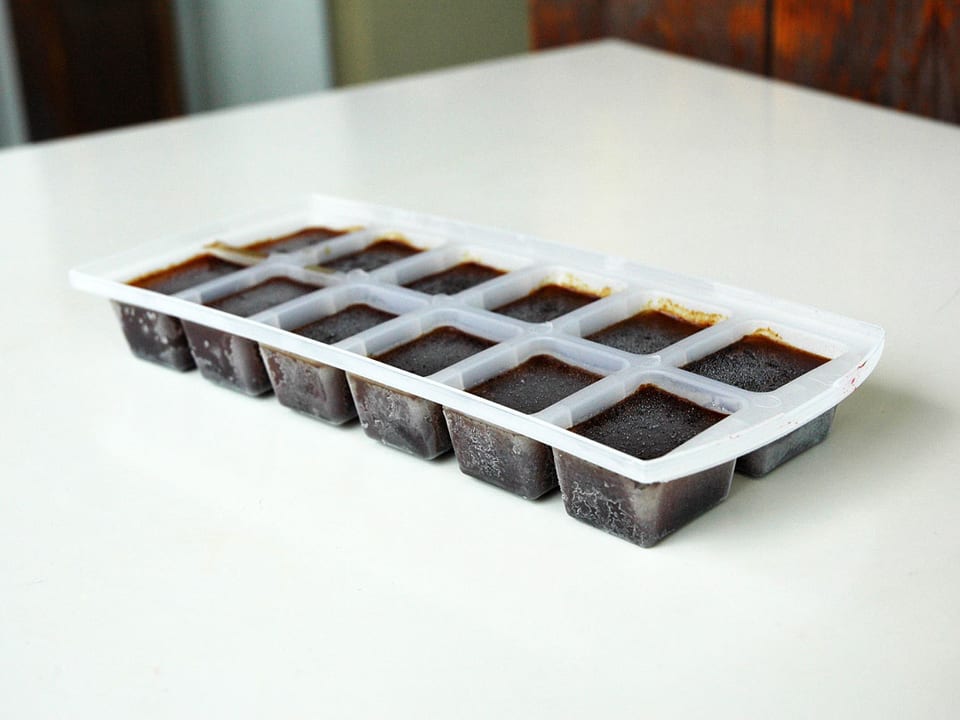 Kaffee-Eiswürfel in einem Eiswürfel-Behälter auf einem weissen Tisch.