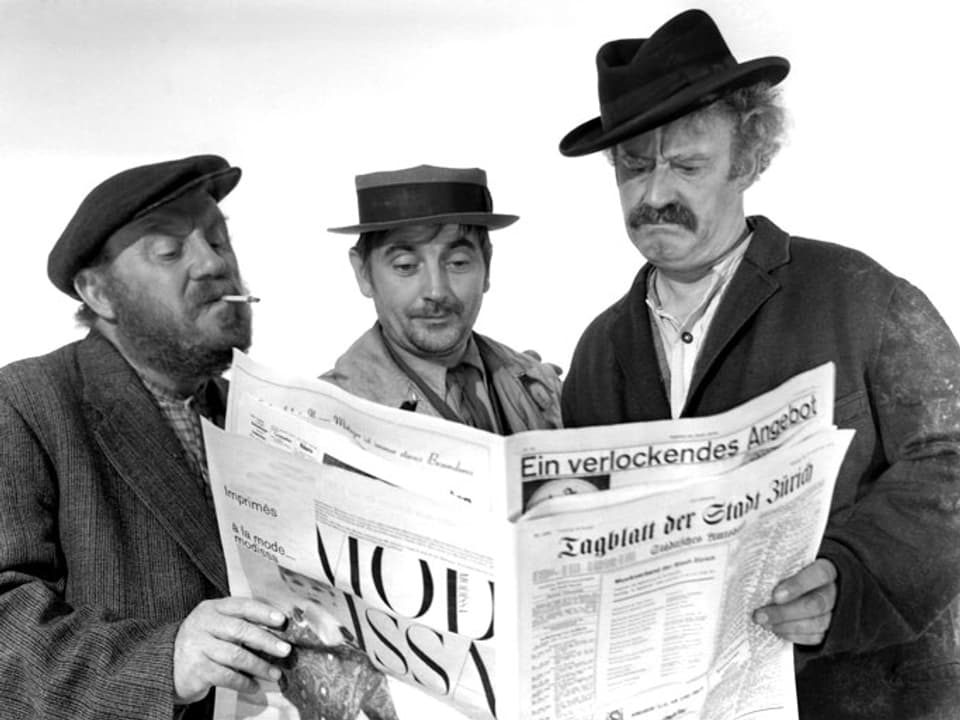 Drei Männer lesen zusammen in einer Zeitung.