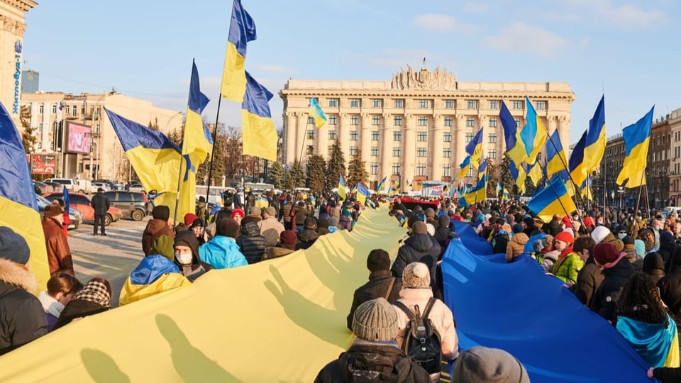 Menschen demonstrieren in Charkiw mit ukrainischen Flaggen.