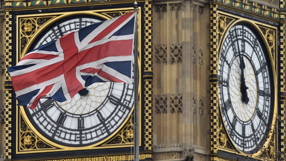 Eine britische Flagge weht vor einer Turmuhr. Sie zeigt Fünf vor Zwölf.