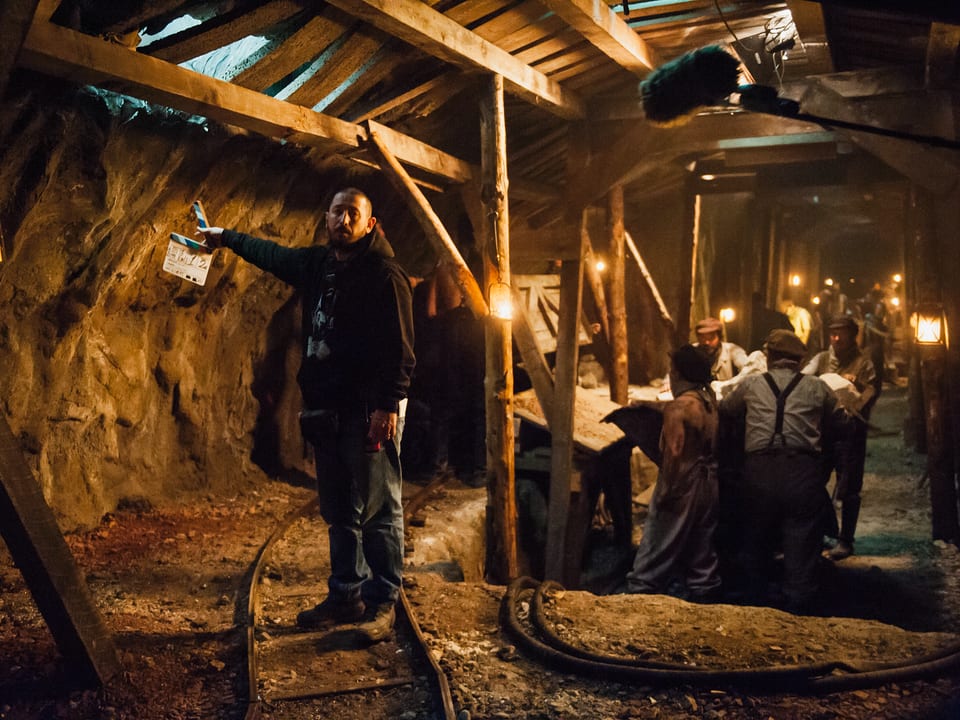 Ein Mann steht mit Filmklappe in einem Tunnelnachbau.