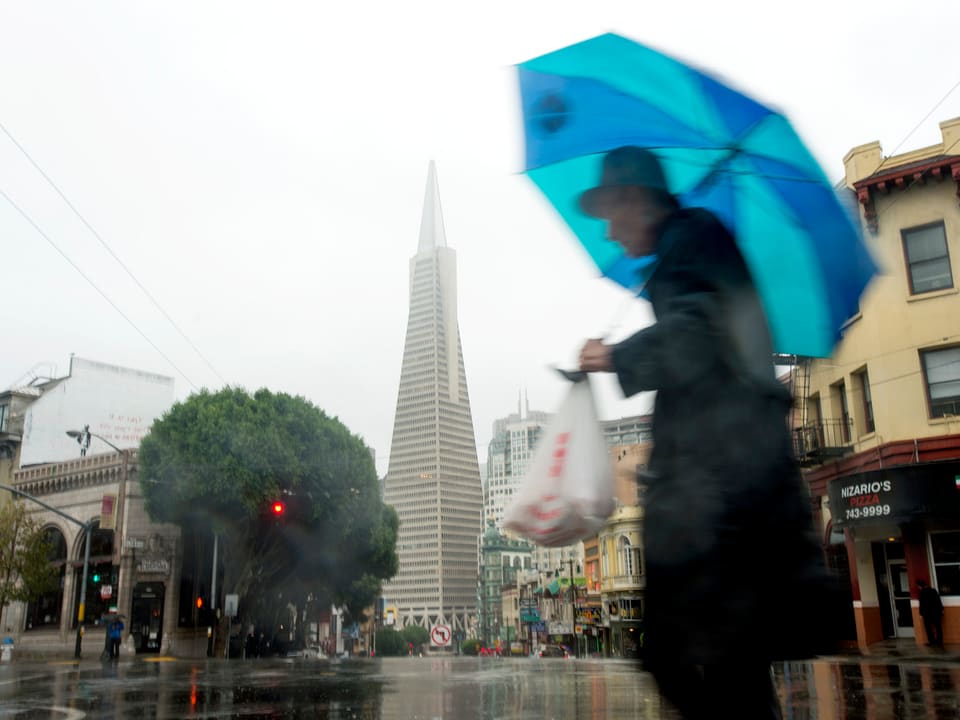 Eine Person mit Regenschirm geht in San Francisco auf der Strasse.