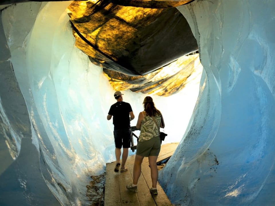 Touristen unter den Eisschutzdecken im Rhonegletscher.