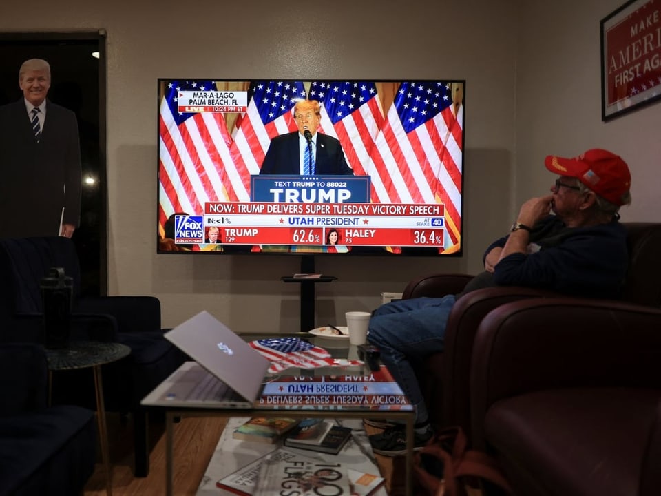 Mann schaut TV. Darauf ist Trump zu sehen.