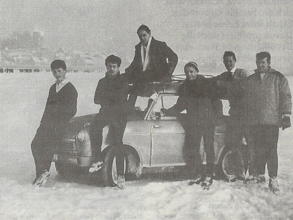 Männer posieren mit einem Auto auf dem gefrorenen See.
