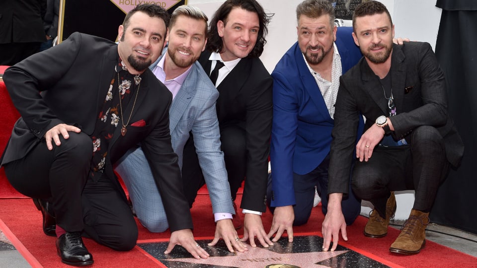 Fünf Männer knien und berühren einen Stern auf dem Hollywood Walk of Fame.