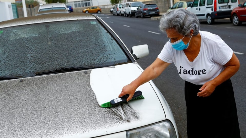 In Los Llanos de Aridane wischt eine Frau Asche vom Auto.