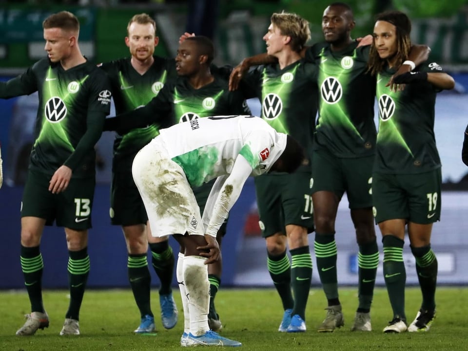 Breel Embolo ärgert sich nach Gladbachs 1:2-Niederlage, während die Wolfsburg-Spieler feiern.
