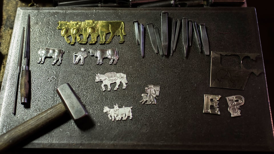 Fein bearbeitete Kühe und Geissen aus Silber und Messing, Nägel und ein Hammer.