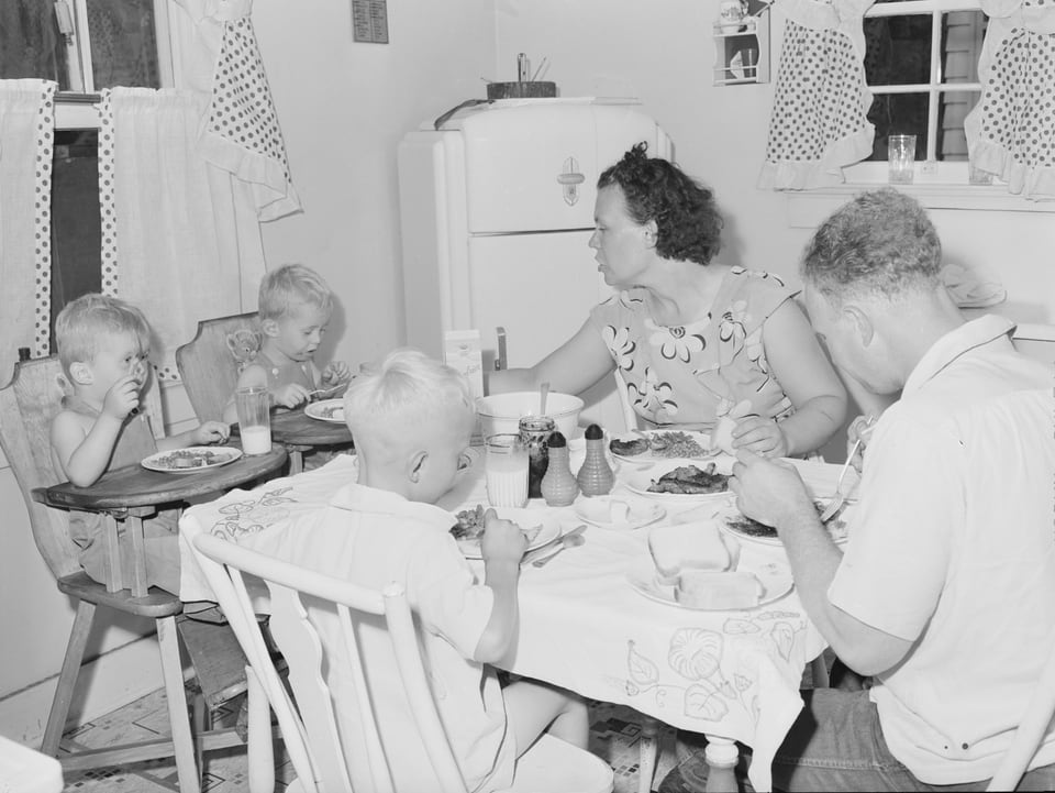 Eine Familie mit drei Jungen sitzen am Tisch und essen.