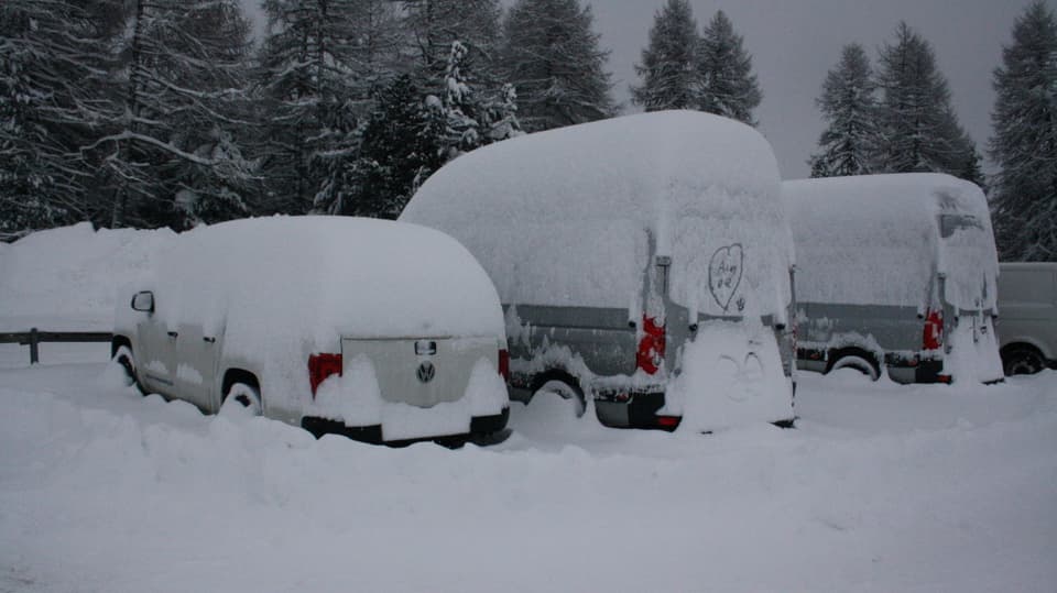 Tief verschneite Fahrzeuge in Salastrains im Engadin.