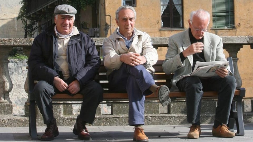 Drei ältere Männer auf Bank sitzend