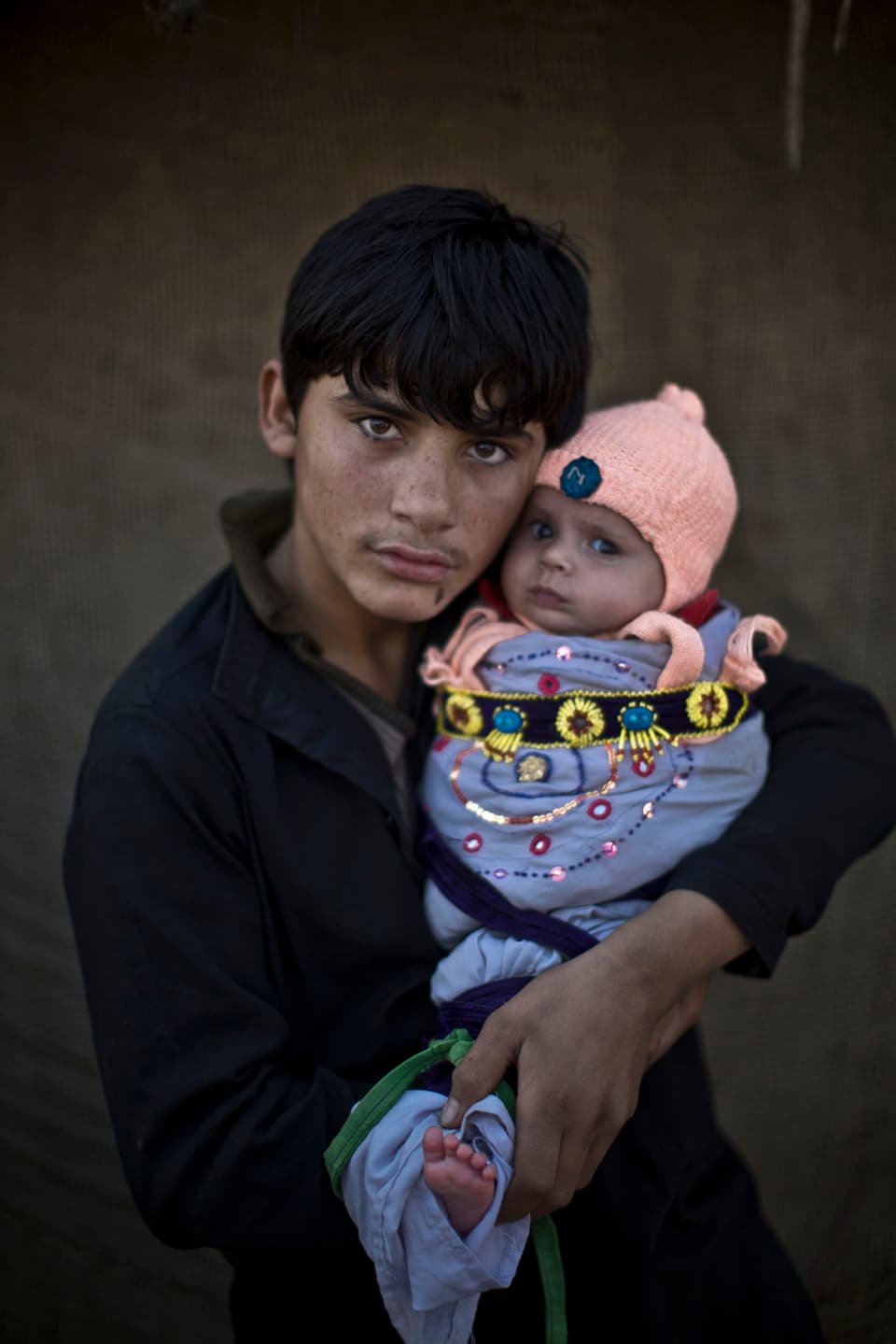 Afghanischer Flüchtlingsjunge hält seinen Cousin im Arm 