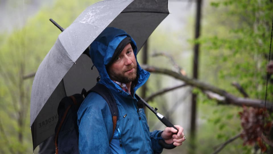 Nik Hartmann mit Schirm im strömenden Regen. 