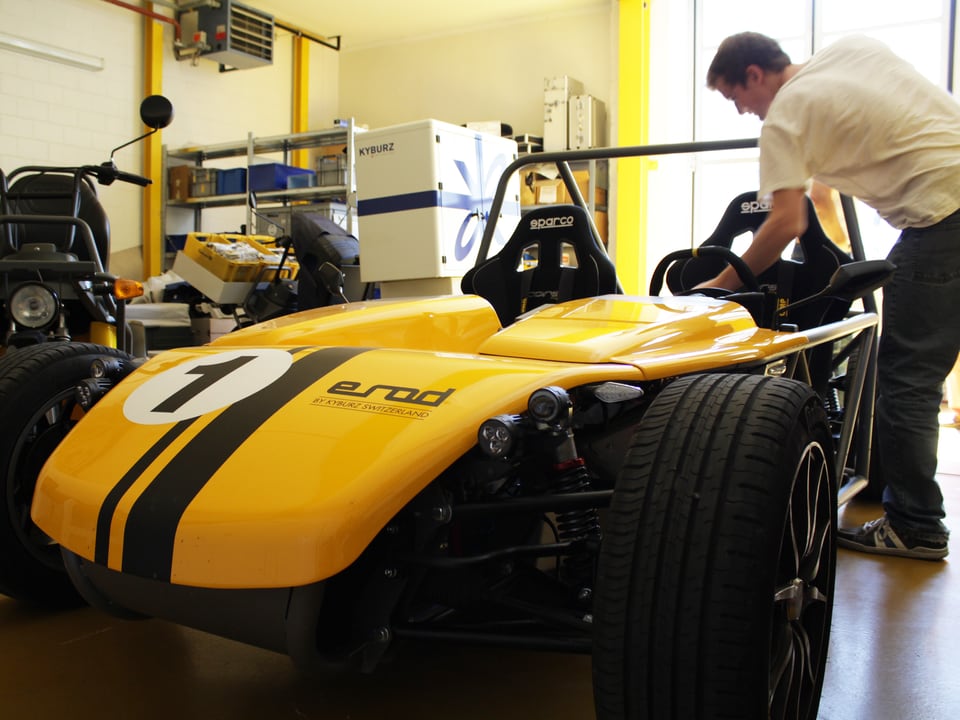 Ein gelbes Elektromobil im Rennwagen-Design in einer Werkhalle.