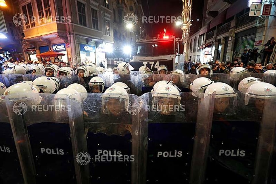 Polizisten in Helmen und mit Schildern auf einer Strasse in Istanbul.