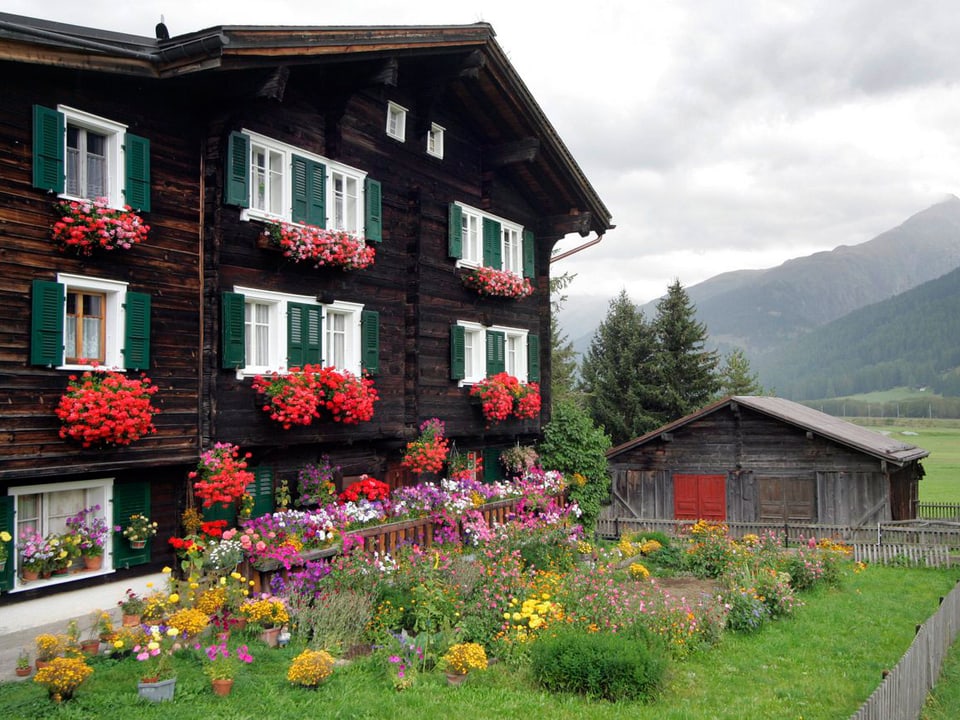 Haus im Wallis ist mit Geranien dekoriert.