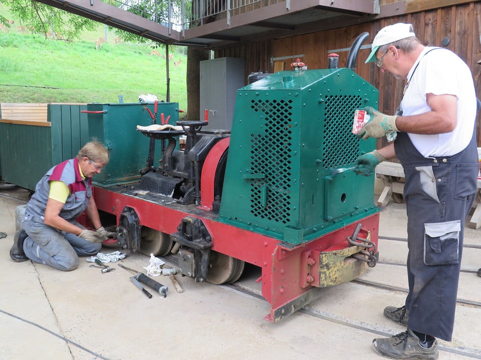 Zwei Männer reparieren die Lokomotive der Stollenbahn.
