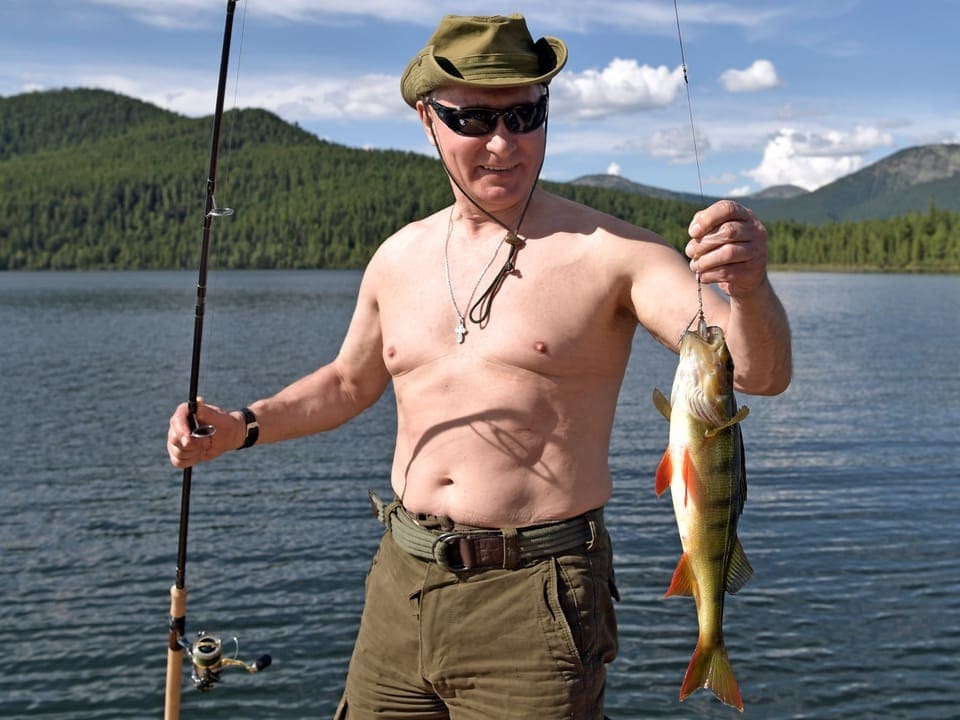 Wladimir Putin hält einen Fisch in der Hand.