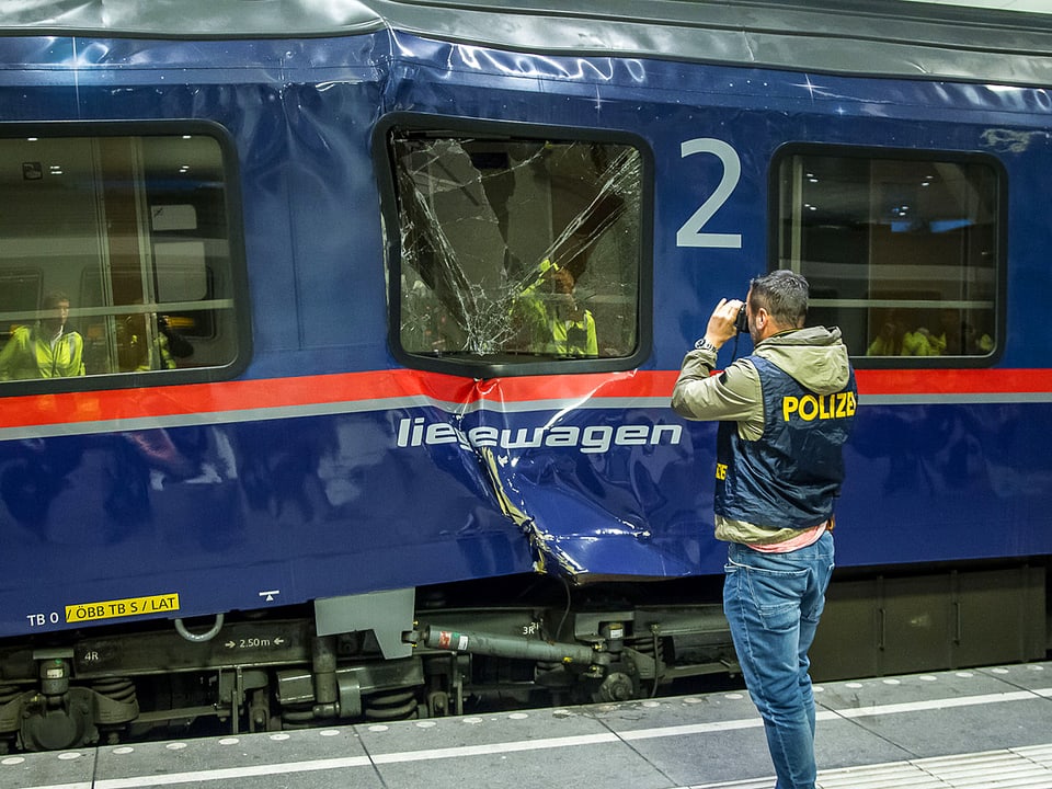 Polizist fotografiert beschädigten Zug.