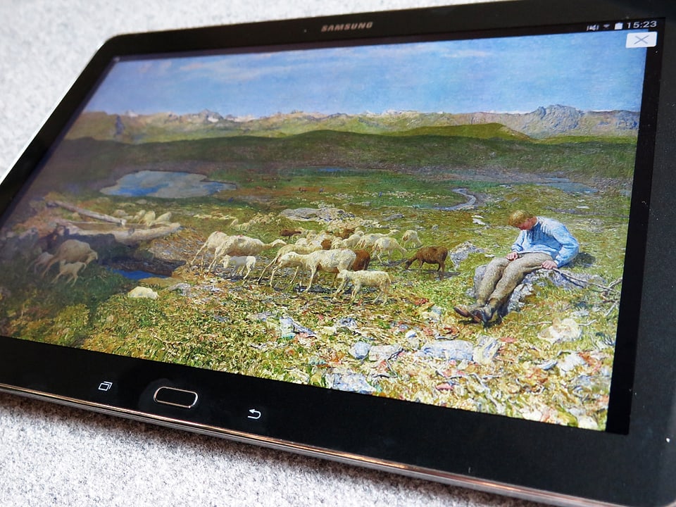 Ein Tablet zeigt ein Gemälde von Giovanni Segantini: Berge, Schafe, ein Hirtenjunge, Wiesen.