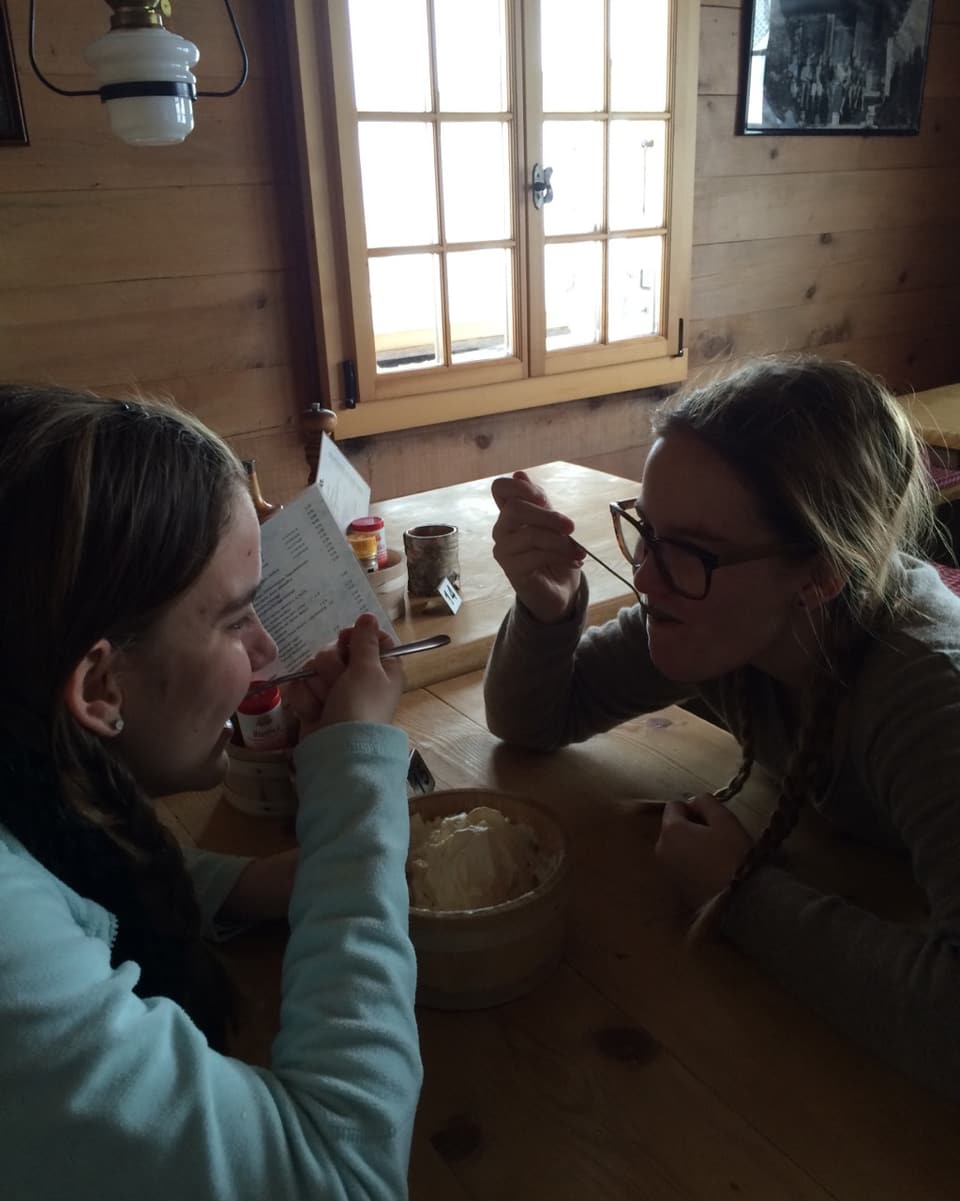 Sarah und Lea beim Meringues essen auf der Axalp, draussen ist es nicht schön.