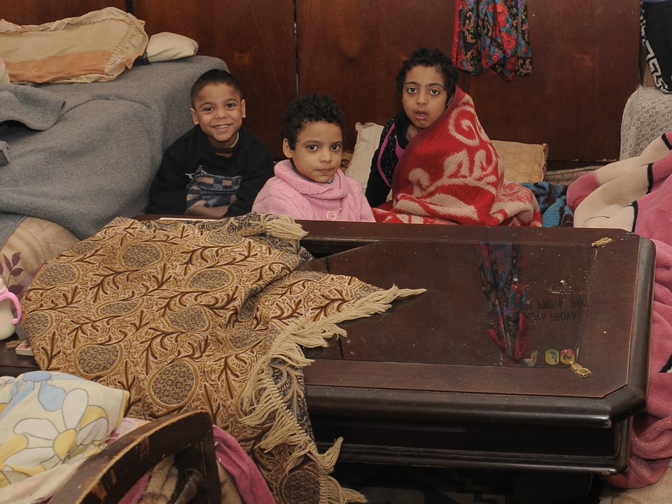 Kinder einer Flüchtlingsfamilie sitzen auf dem Boden. 