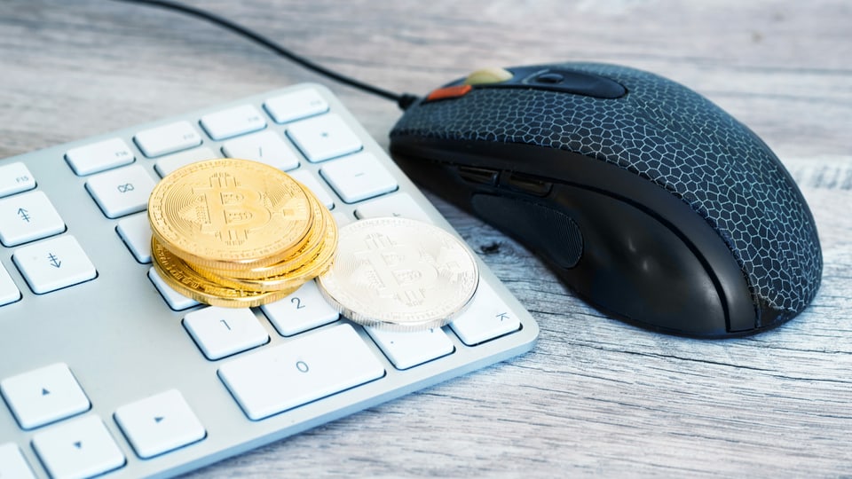 Symbolbild: Tastatur mit goldenen Bitcoin Münzen