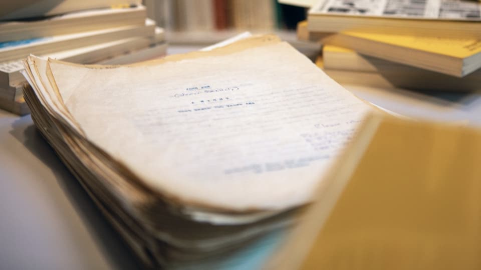 Ein Stapel alter vergilbter Papiere liegt auf einem Tisch.