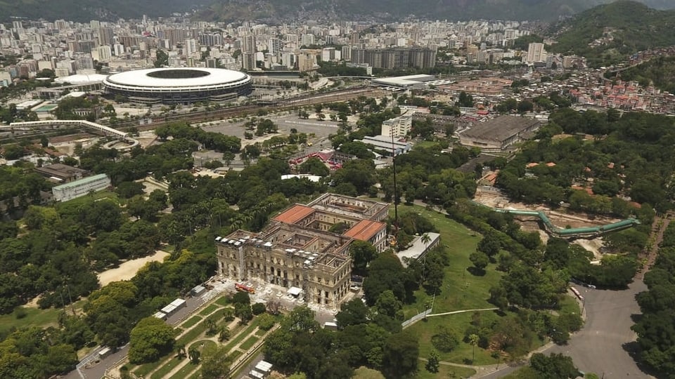 Luftaufnahme des zerstörten Museumsgebäudes. Im Hintergrund ein modernes Fussballstadion