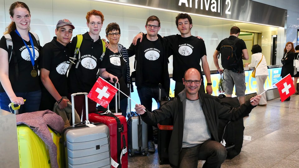 Fünf Schüler mit Digitalredaktor Reto Widmer, der zwei Schweizerfähnchen hält.