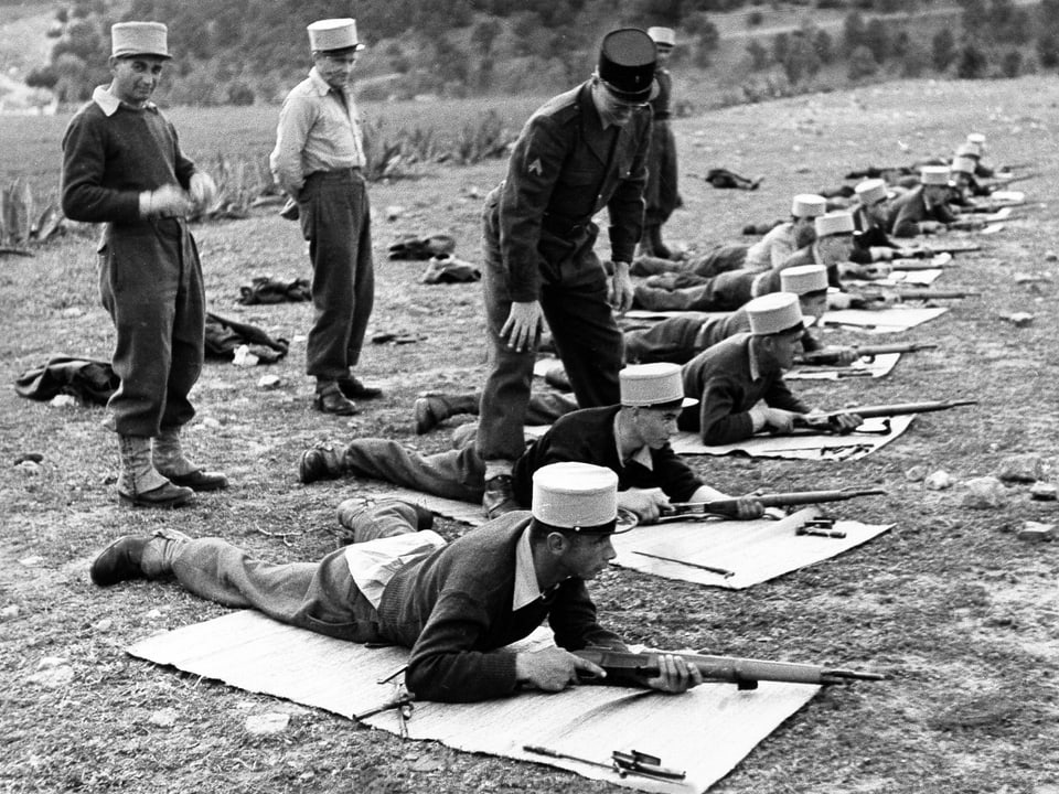 Soldaten mit weissem Käppi liegend in einer Reihe beim Schiessen.