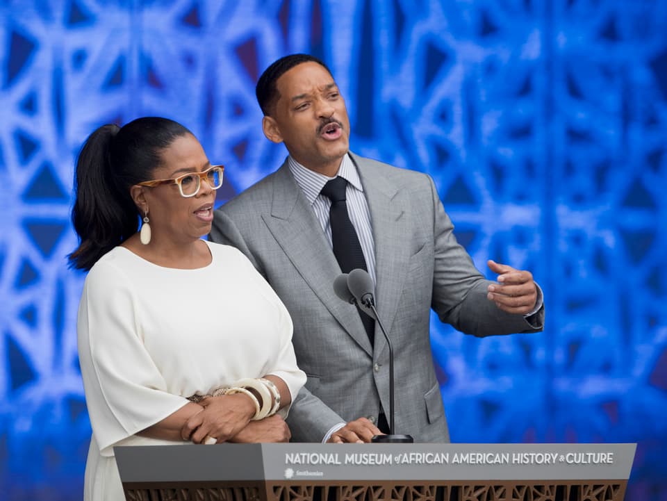 Oprah Winfrey und Hollywoodstar Will Smith stehen an einem Rednerpult