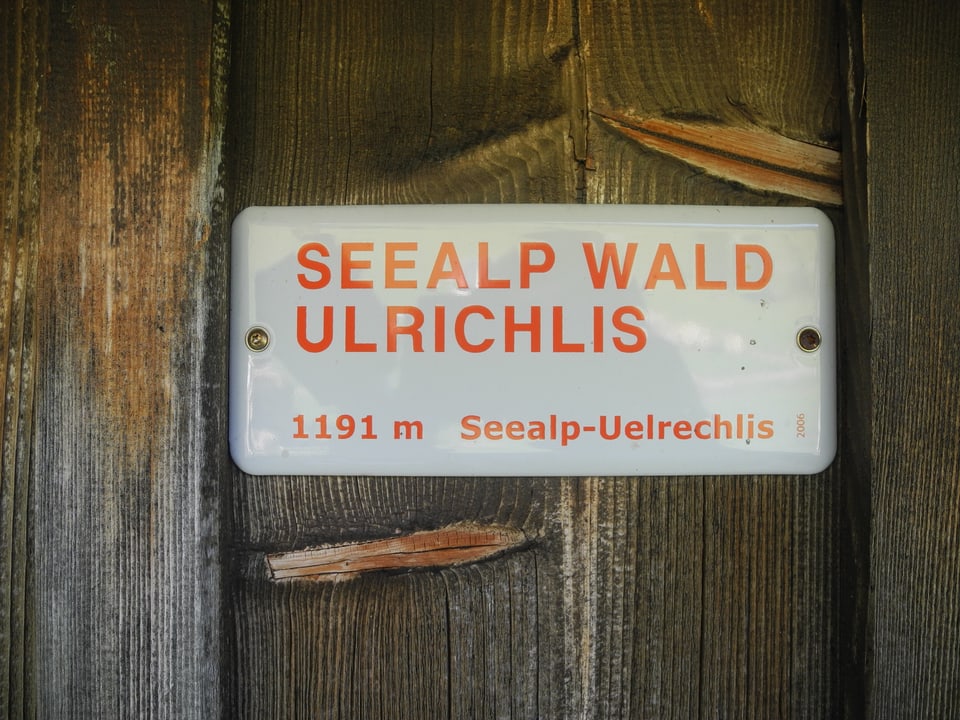 Auf dem Schild an der hölzernen Hauswand steht: «Seealp Wald Ulrichlis – 1191m Seealp-Uelrchlis»
