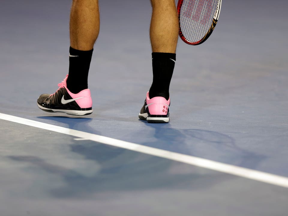 Federers Füsse in schwarz-pinken Schuhen.