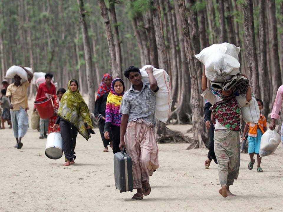 Mit ihrem Hab und Gut auf dem Rücken bringen sich Bangladescher vor dem Sturm in Sicherheit.