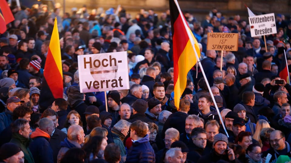 Menschen stehen herum, es sind Deutschlandfahnen und Transparente zu sehen, auf einem steht «Hochverrat».