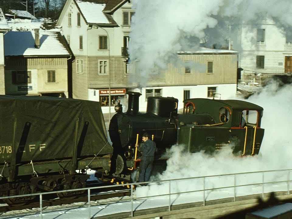 Eine historische Lokomotive stösst einen Zug eine Rampe hinauf.