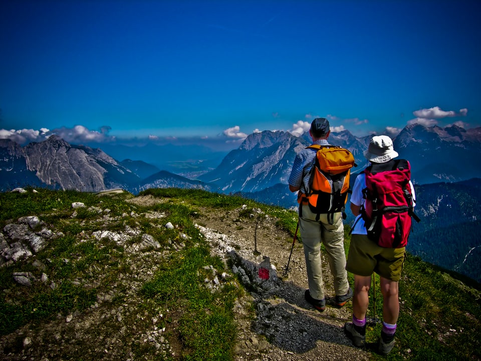 Zwei Wanderer vor Bergpanorama.