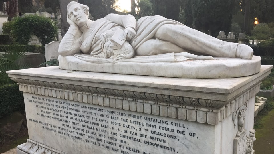 Ein Grabstein mit der Skulptur eines Mannes.