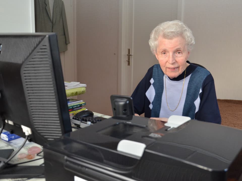 Helen Hält am Schreibtisch vor dem Computer.