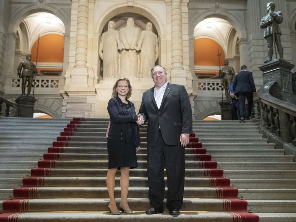 Frau und Mann geben sich die Hand auf der Treppe im Eingangsbereich des Bundeshauses.
